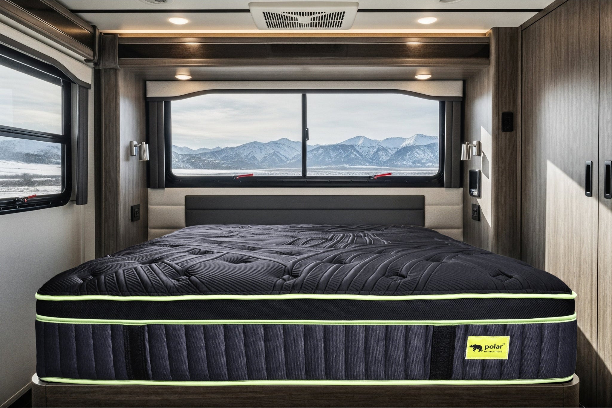 Black RV mattress with a brand logo in a vehicle interior with windows showing mountains.