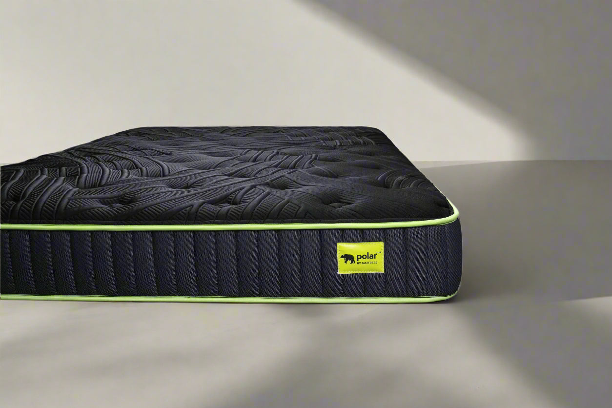 Black camping mattress with green logo on a gray surface