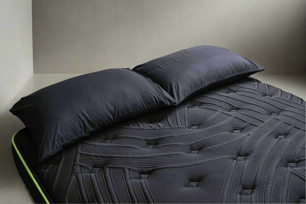 Dark gray quilted rv mattress cover with two pillows on a white background